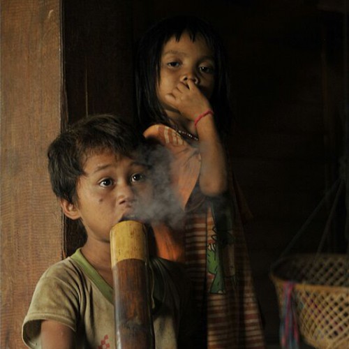 Children and adults alike smoke from a bamboo tobacco bong in some small villages in Lao